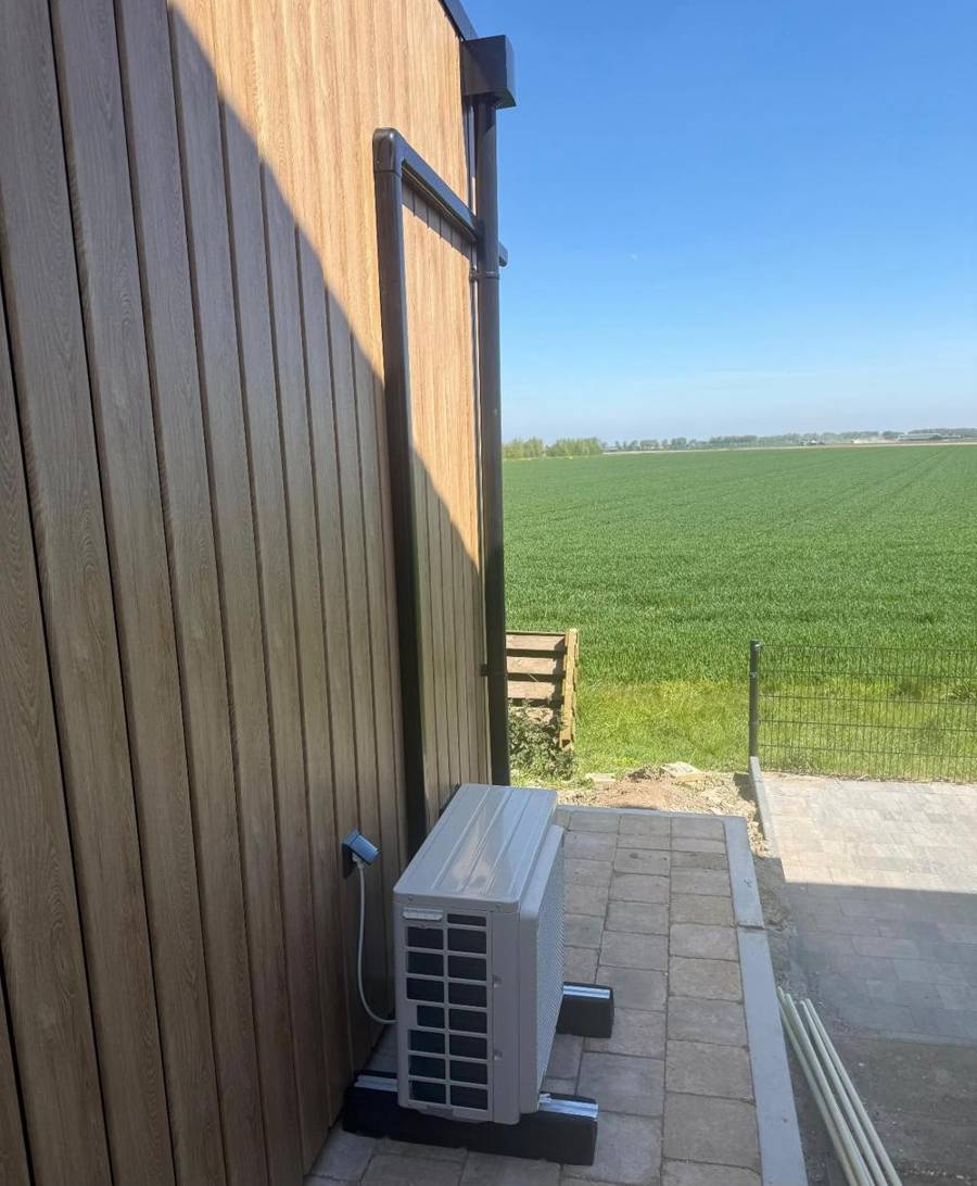 Buitendeel op voeten naast een houten gevel met leidinggoot